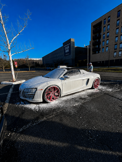 Audi R8 Spyder covered in thick snow foam on a sunny lot