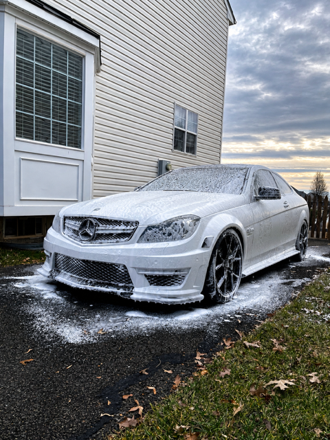 Mercedes-AMG C63 coupe covered in snow foam during a driveway pre-wash