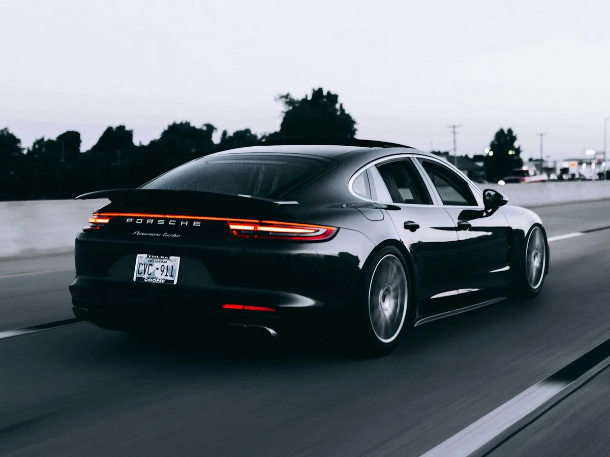 Black luxury sedan at dusk with deep gloss reflections along the body line